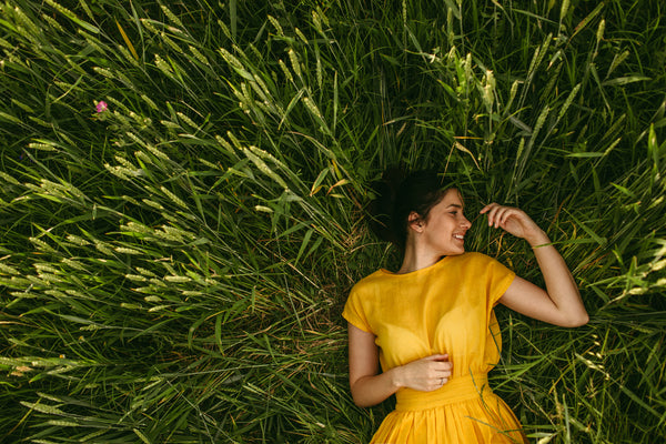 A woman laying on a field of grass - enjoying the positive effects of CBD  