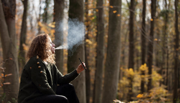 A woman exhaling a vape cloud from her Infused Amphora effects-based CBD Vape Cartridge and Vape Pen 