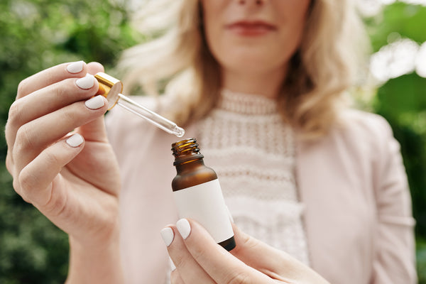 A woman extracting CBD Oil drops from a bottle. Amphora's effect based CBD Products  