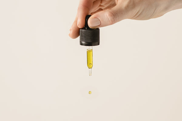 dropper being squeezed by hand to release Infused Amphora high strength cbd oil drops