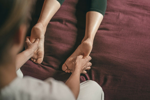 A man massaging the feet of a woman with CBD Lotion as she lies flat on a bed  