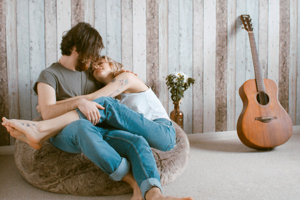 Couple hugging playfully on a bean bag chair after using CBD for sex. 