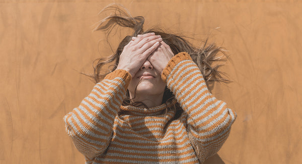 A woman in a cornfield covering her eyes anxiously. CBD for anxiety  