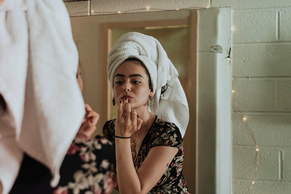A woman applying her makeup and incorporating CBD topicals in her skincare routine