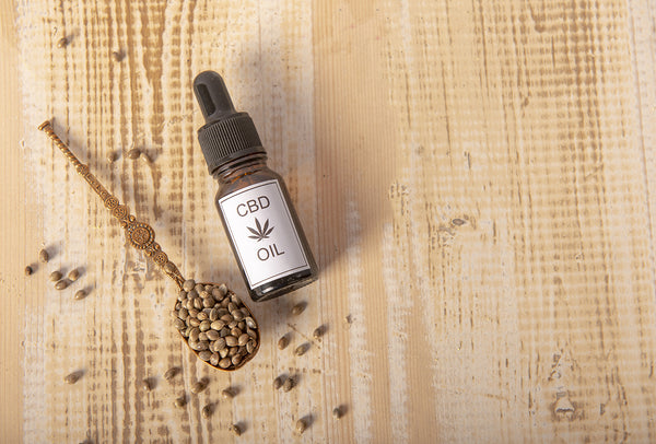 CBD Oil next to a wooden spoon full of herbs. The history of CBD 