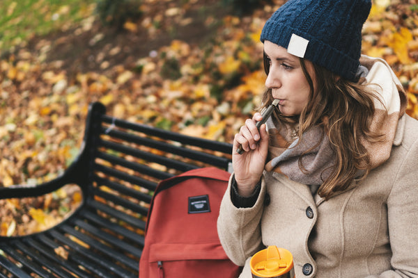 women on park bench in fall vaping an Amphora CBD vape cartridge