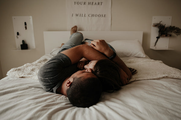 A man and woman lay in a bed, embracing after experiencing increased libido with CBD