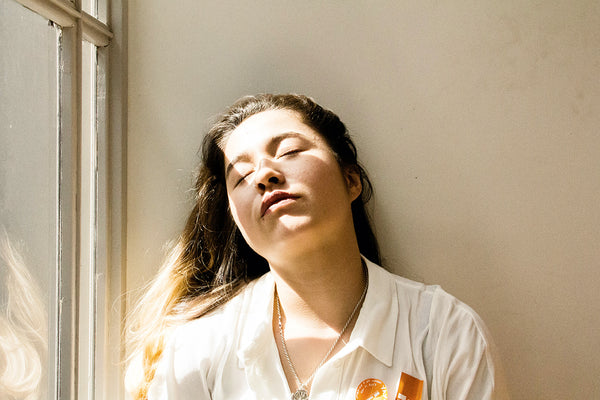 woman leaning against wall near window exhausted from pandemic fatigue