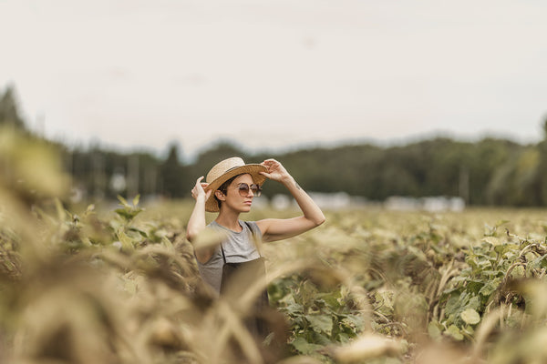 A woman standing in a field of organic hemp plants. Experiencing the positive wellness effects of CBD  