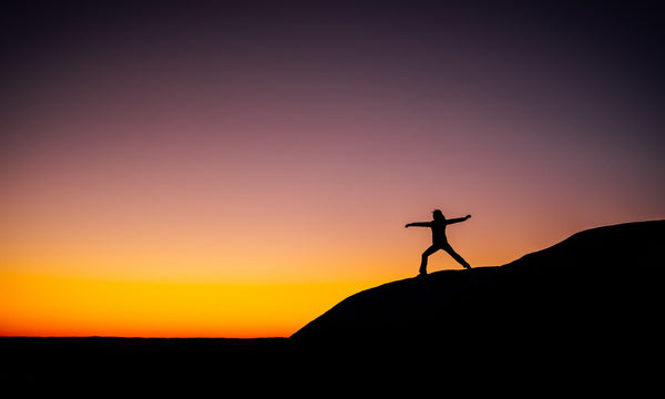 person performing yoga at sunset on a hill after taking CBD